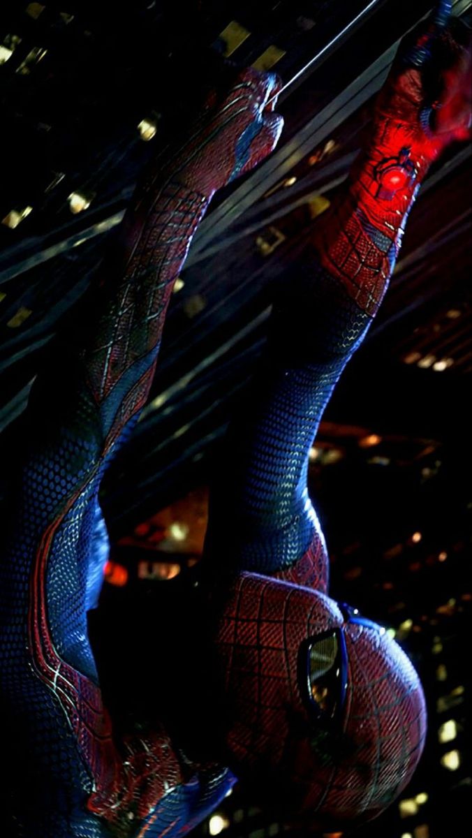 the amazing spider - man is hanging upside down in the air with his arms stretched out