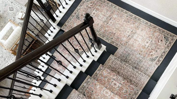 an overhead view of a stair case with rugs on the floor and stairs to the second floor