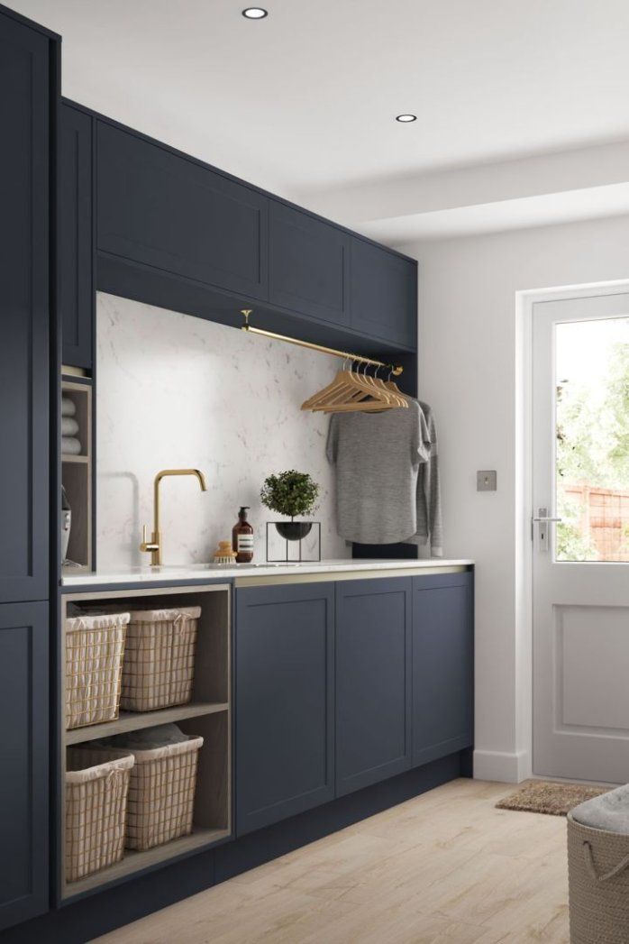 a kitchen with dark blue cabinets and white counter tops, an open door to the outside