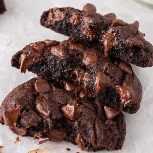 three chocolate cookies stacked on top of each other with one bite taken out of it