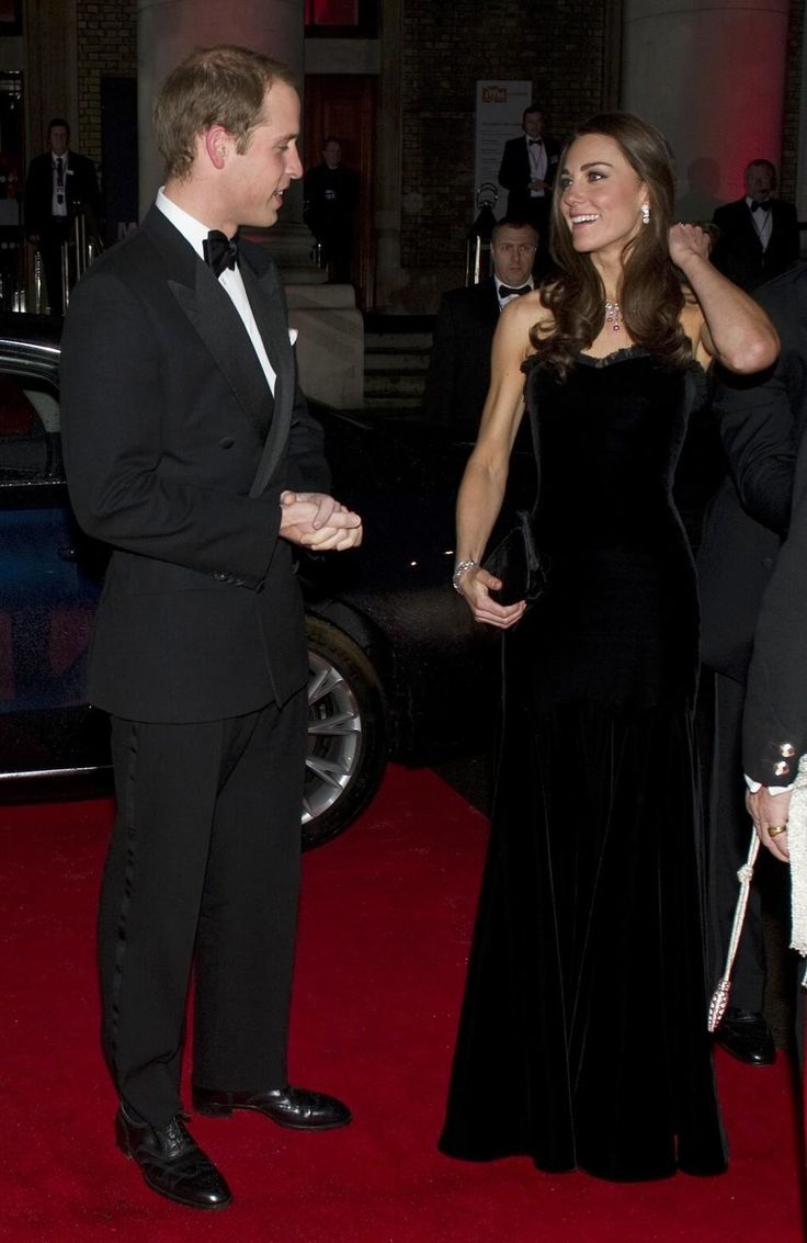 a man and woman in formal wear talking to each other on the red carpet at an event