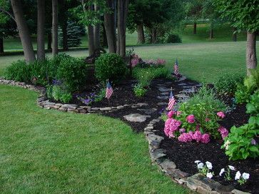 a garden with flowers and flags in the middle of it, surrounded by trees on both sides