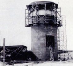 an old black and white photo of a lighthouse with scaffolding on it's side