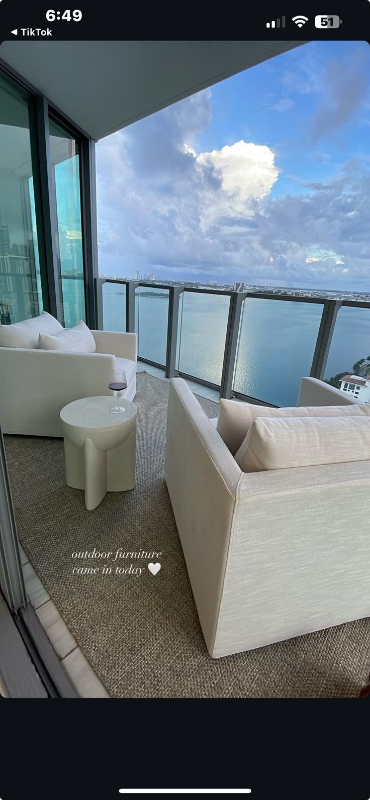 a living room filled with white furniture next to a large glass window overlooking the ocean