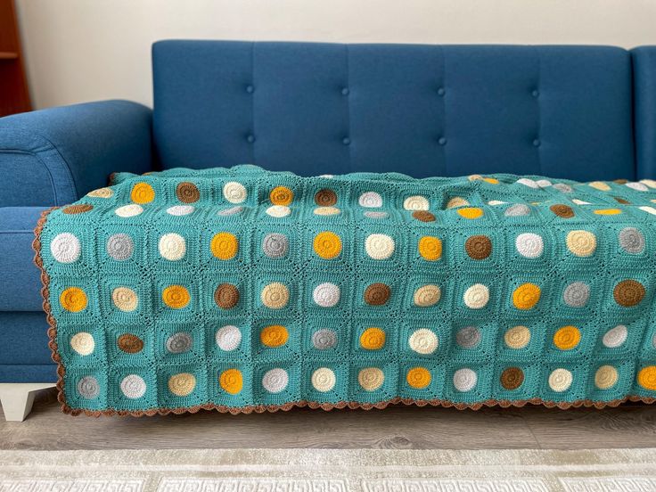 a blue couch with a crocheted blanket on it