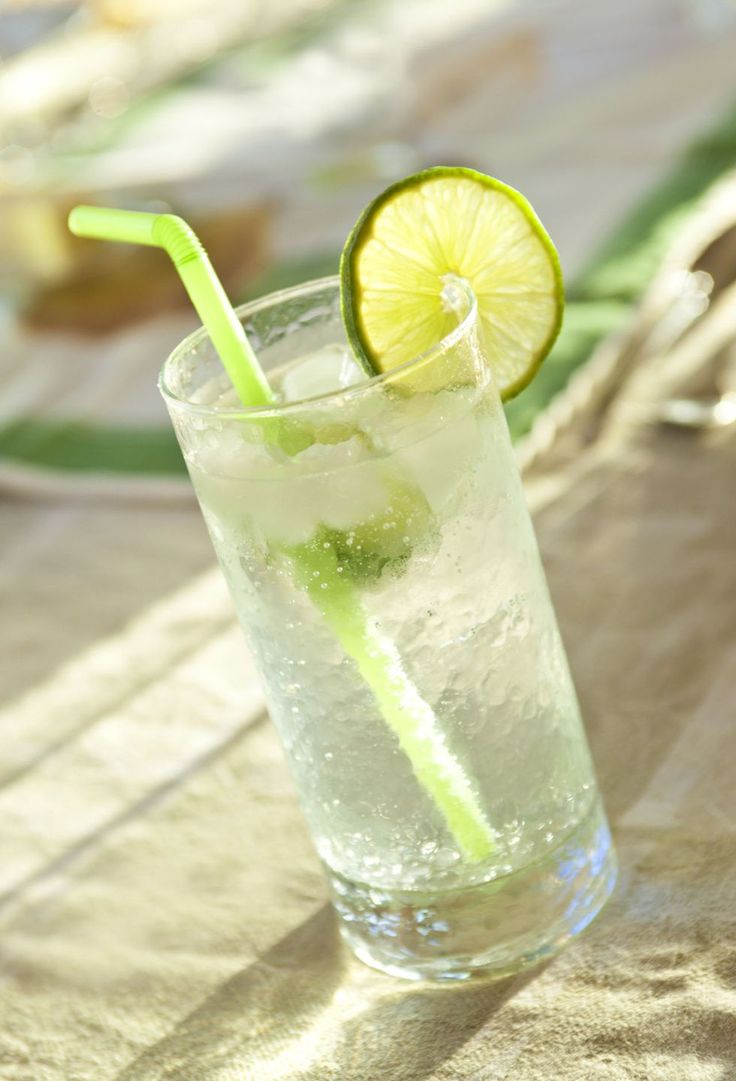 a glass filled with ice and lime on top of a table