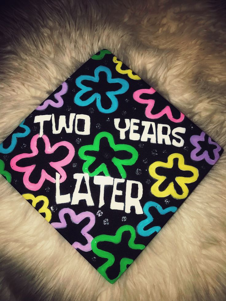 a graduation cap with the words two years later written in multicolored letters on it