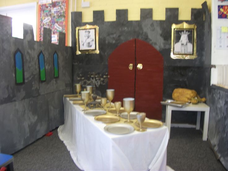 a table with plates and cups on it in front of a castle like wall that is painted yellow