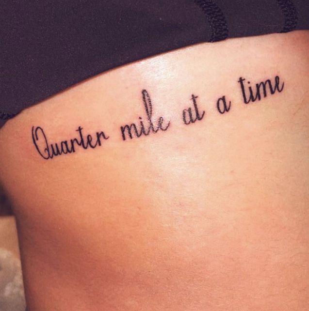 a woman's stomach with the words quanter mile at a time tattooed on it