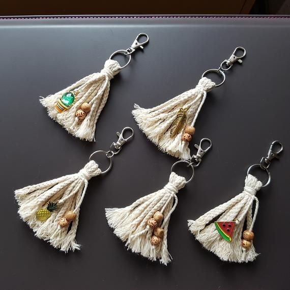 four tasseled keychains with beads and charms hanging from them on a table