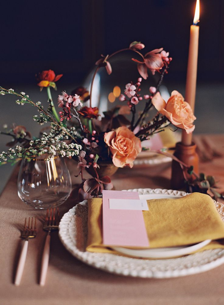 a place setting with flowers and candles on the table