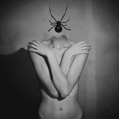 a black and white photo of a naked woman with a spider on her head above her head