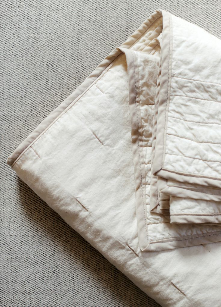 a pile of folded white linens sitting on top of a carpet