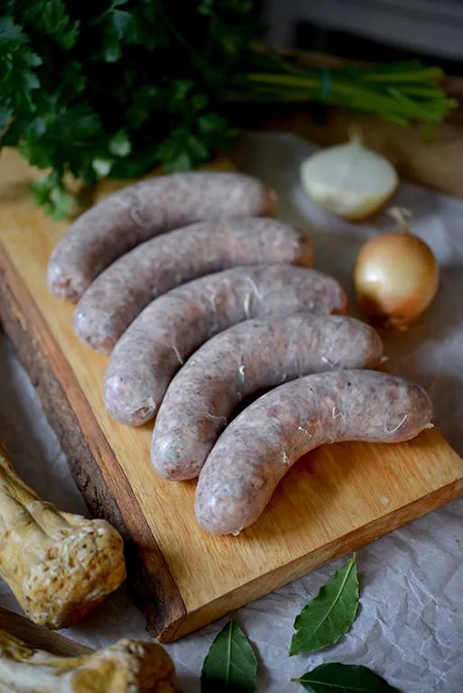 several sausages are on a cutting board next to vegetables