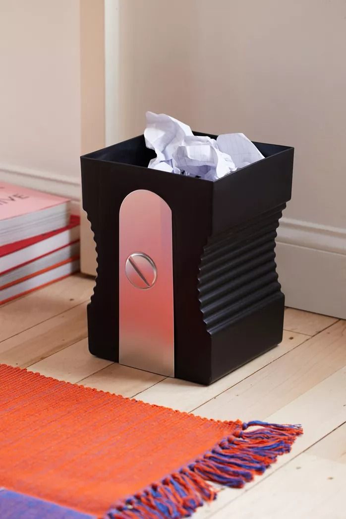 a tissue dispenser sitting on top of a wooden floor next to a pile of books