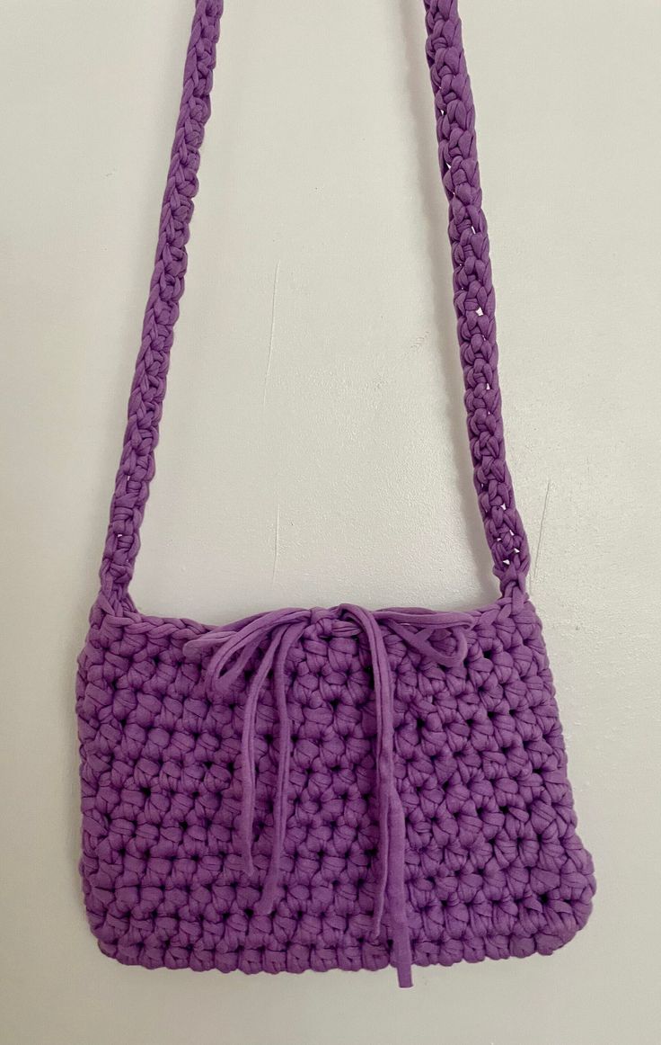 a purple crocheted purse hanging on a wall