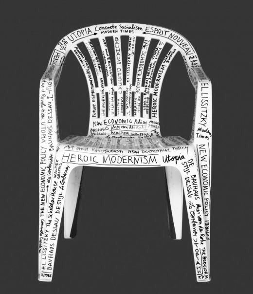 a white plastic chair with words written all over the back and sides, on a gray background