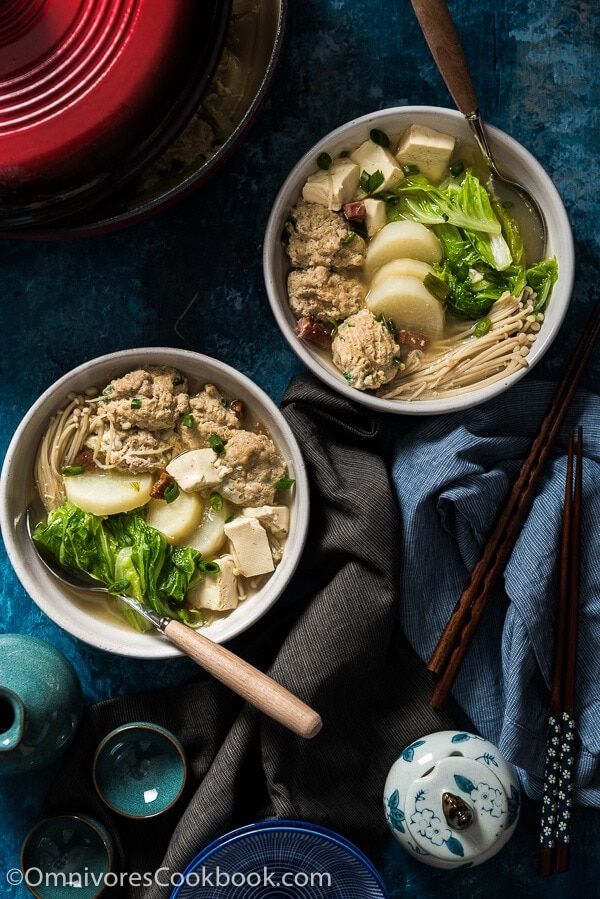 two bowls filled with food next to chopsticks on a blue table cloth and plates