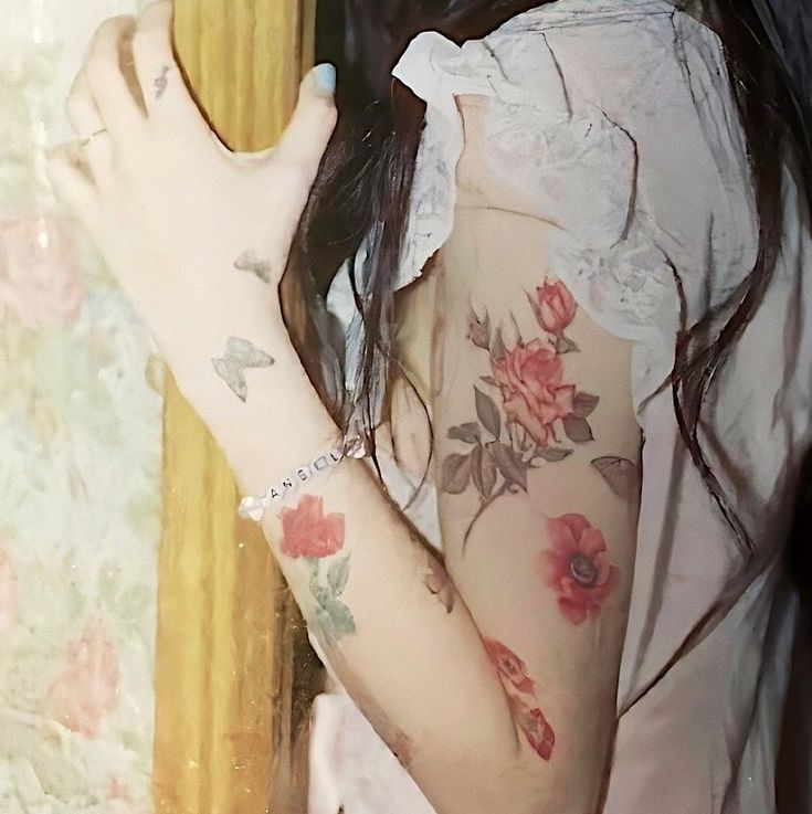 a woman with flowers on her body and arm holding a mirror in front of her face