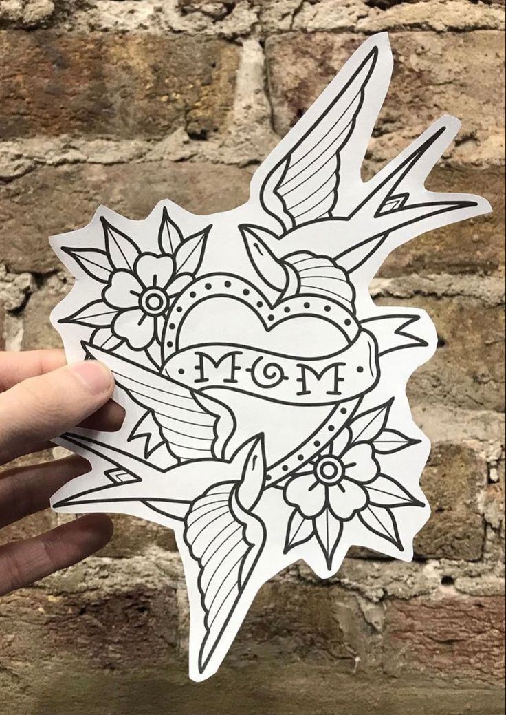 someone holding up a sticker with the word mom on it in front of a brick wall