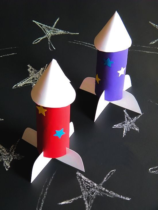 two paper rockets sitting on top of a black table next to star shaped confetti cones