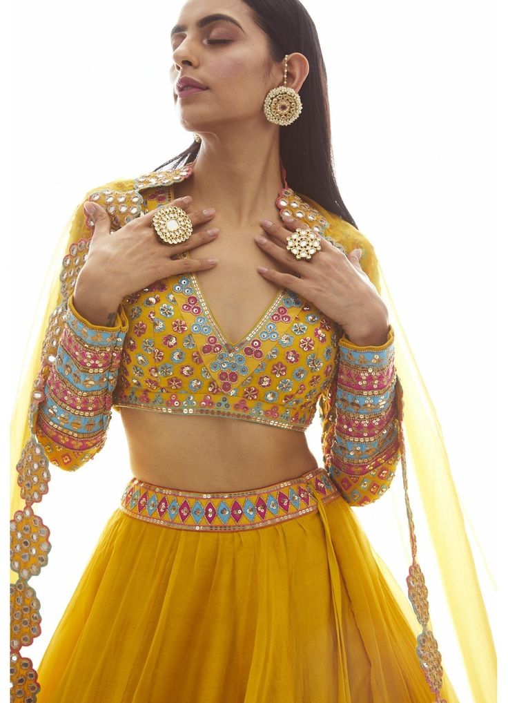 Step into elegance and radiate confidence with our Mustard Yellow Applique Lehenga Set. This exquisite ensemble features a beautifully hand-embroidered blouse adorned with stunning applique work. The skirt, crafted from luxurious silk organza, is enhanced with a mesmerizing mirror border that adds a touch of glamour. Complete the look with the matching dupatta, and you'll be the epitome of grace and style. Perfect for weddings, festivals, or any special occasion, this Lehenga Set from Vani is a true masterpiece that will make heads turn. Composition : Lehenga and Dupatta - Organza, Blouse - Georgette, Lining - Silk Blend Care: Dry Clean Only and Vacuum Storage This product can be customized for sleeves, length of blouse and neckline Delivery : 6-8 weeks as the product is hand crafted. Chec Mustard Lehenga, Mirror Lehenga, Vani Vats, Applique Blouse, Indian Outfits Lehenga, Lehnga Dress, Embroidered Lehenga, Indian Gowns Dresses, Trendy Blouse Designs