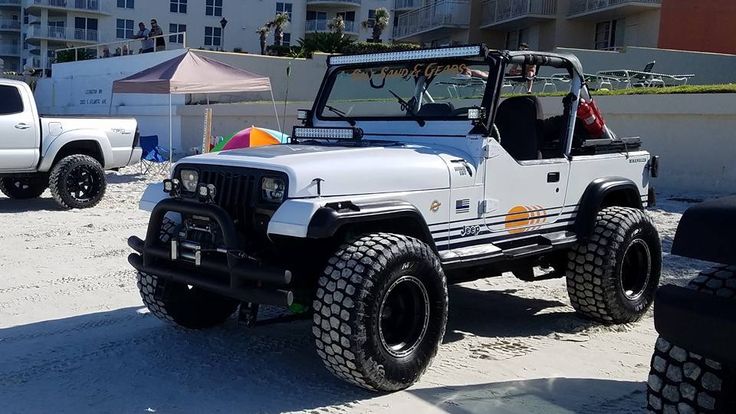 a white jeep is parked in the sand