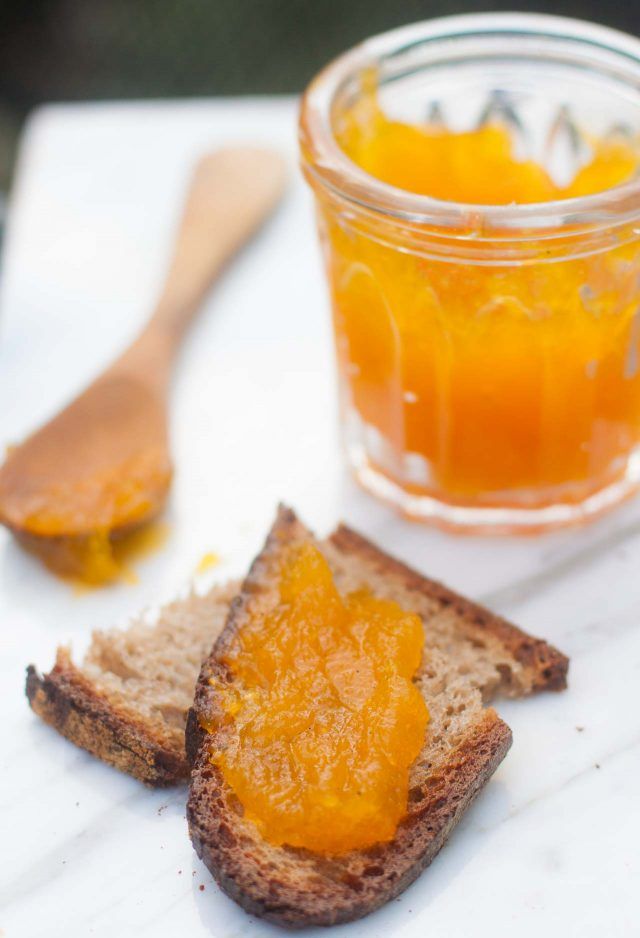 two pieces of bread with orange slices on them next to a jar of honey and spoon