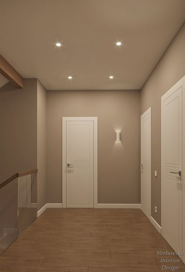 an empty room with two white doors and some wooden stairs in the center is lit by recessed lights