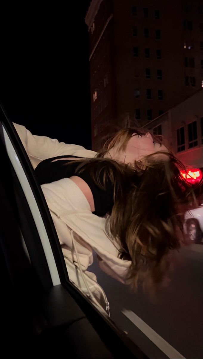 a woman laying down in the back seat of a car at night with her eyes closed