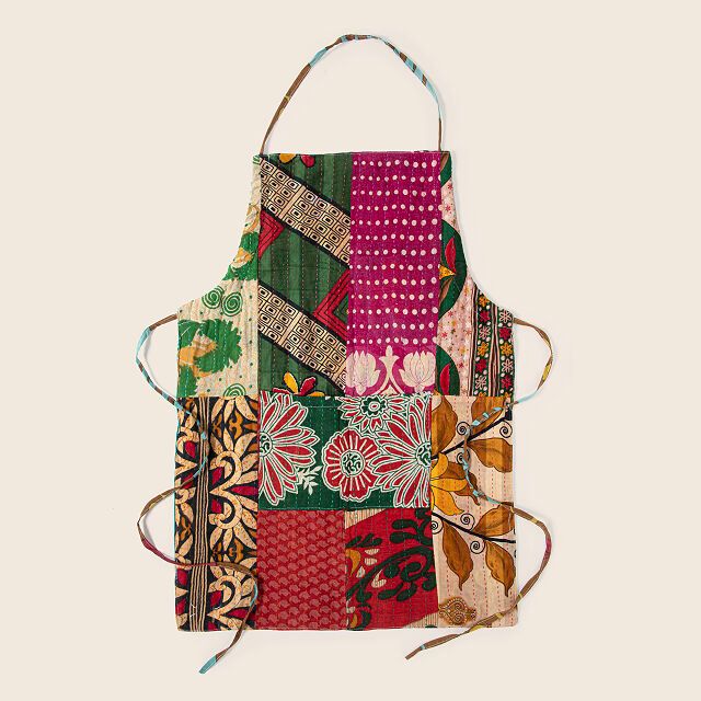 a multicolored patchwork apron with ties hanging from it's front pocket