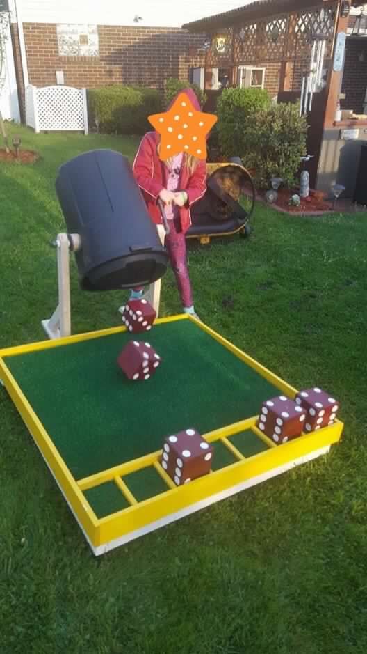 a person in a red jacket and some dices on a green lawn with a yellow frame