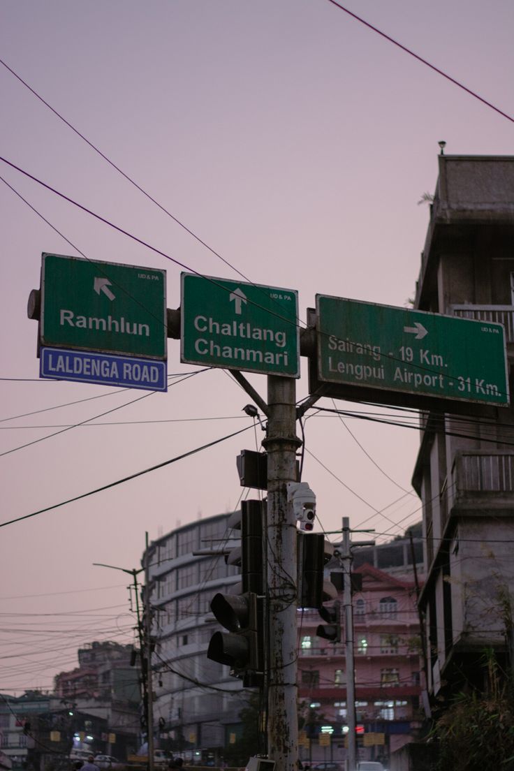 two green street signs mounted to the side of a metal pole next to a traffic light