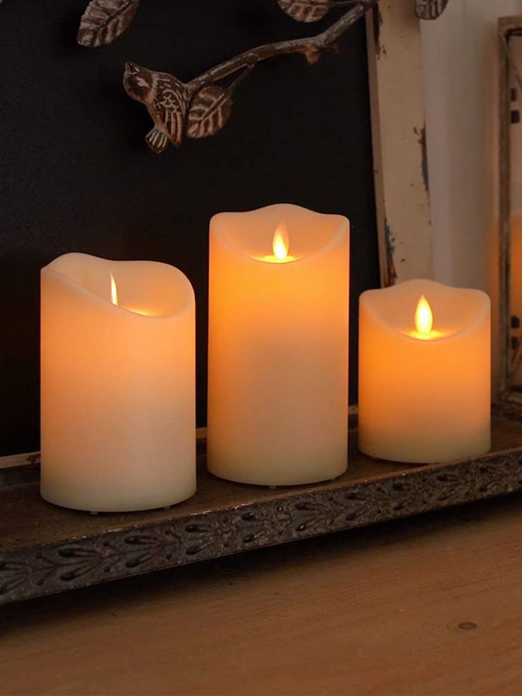 three lit candles are sitting on a shelf