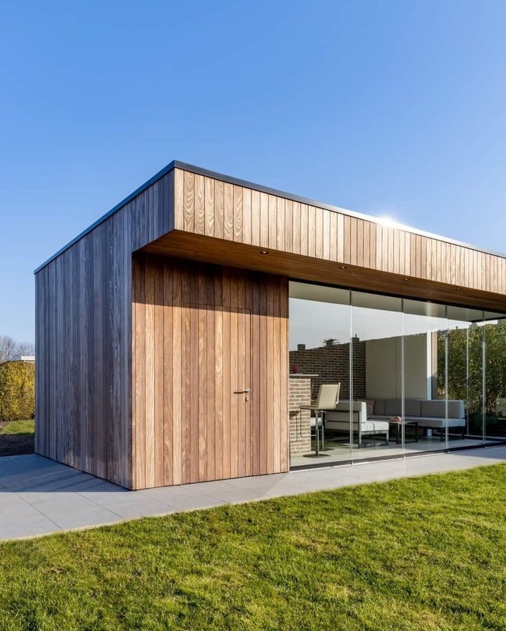 a wooden building with glass walls on the outside and lawn area in front of it