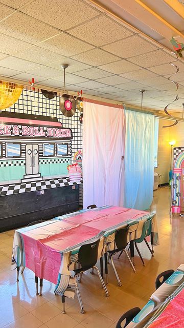 an empty room with tables and chairs in front of a wall mural on the wall