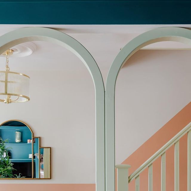 an arched doorway leads to a living room with pink and blue walls