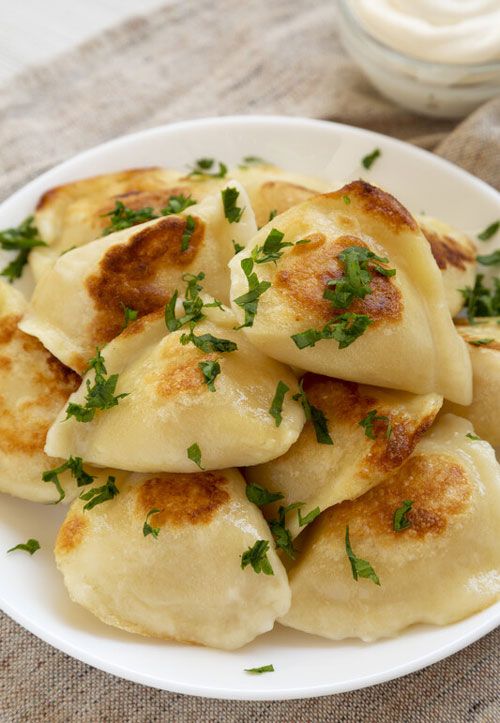 some dumplings are on a white plate and garnished with green parsley