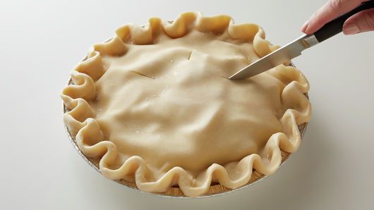 a person cutting into a pie with a knife