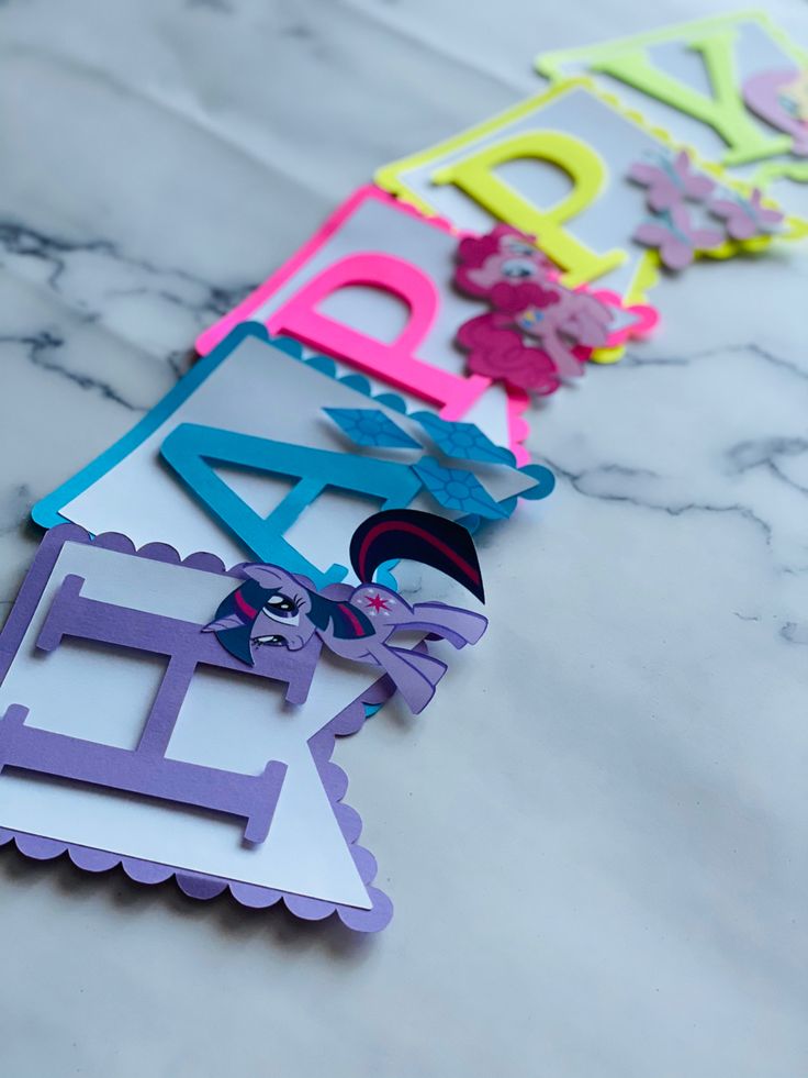 some cut out letters sitting on top of a marble table with scissors and paper flowers