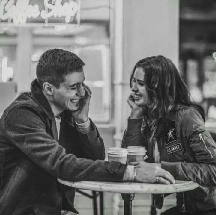 two people sitting at a table talking on their cell phones and drinking coffee in front of a store