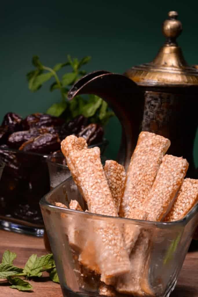 a glass bowl filled with crackers next to a tea pot