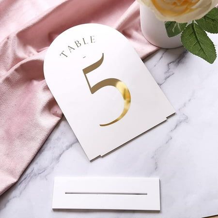 the table numbers are next to a vase with flowers in it on a marble surface