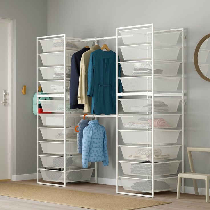 a white closet with clothes and other items on shelves next to a wooden floor in front of a door