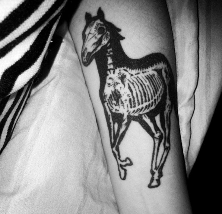 a black and white photo of a horse skeleton tattoo on the left inner arm,