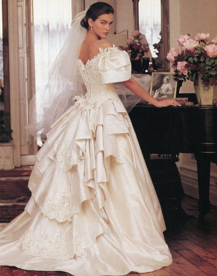 a woman in a wedding dress standing next to a piano