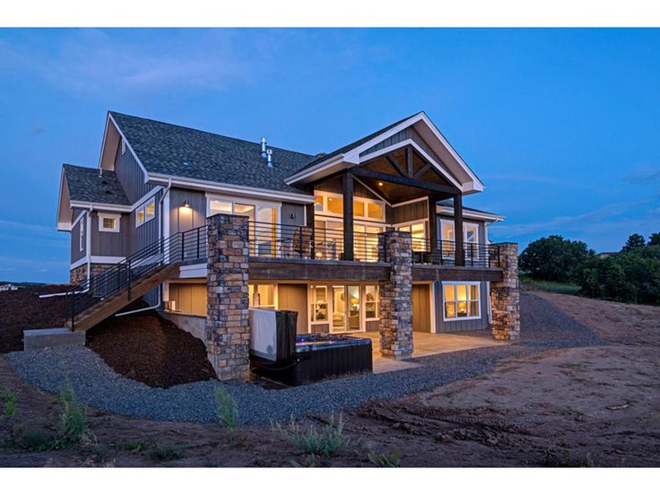 a two story house is lit up at night with lights on the windows and balcony