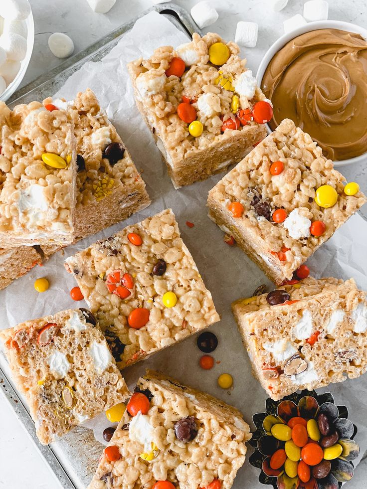 several pieces of rice krispy treats sitting on top of a baking sheet with candy and marshmallows