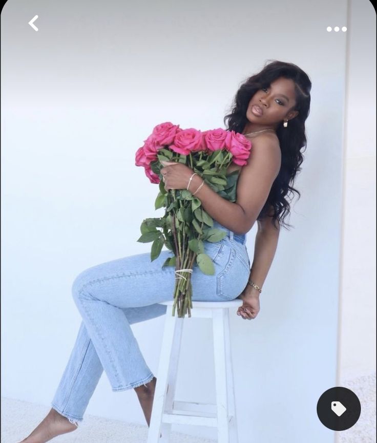 a woman sitting on a stool holding roses