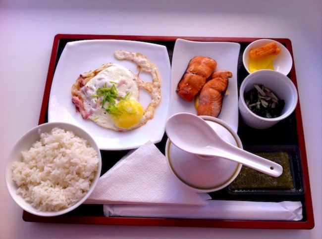 a tray with rice, carrots, eggs and other foods on it is shown